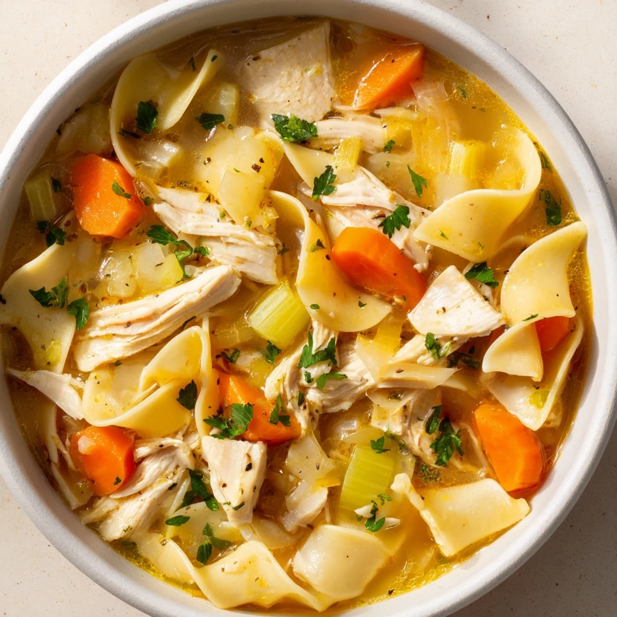 Golden, steaming Cozy Chicken Noodle Soup, full of chunky carrots and perfectly cooked noodles.