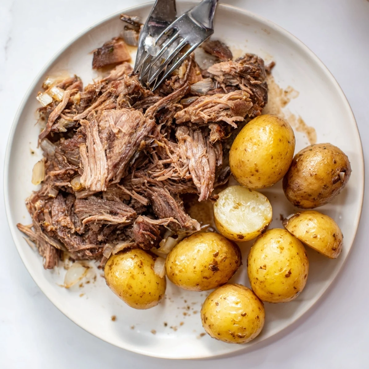 Tender slow cooker pot roast, falling apart with potatoes, rich broth visible in the crock pot.