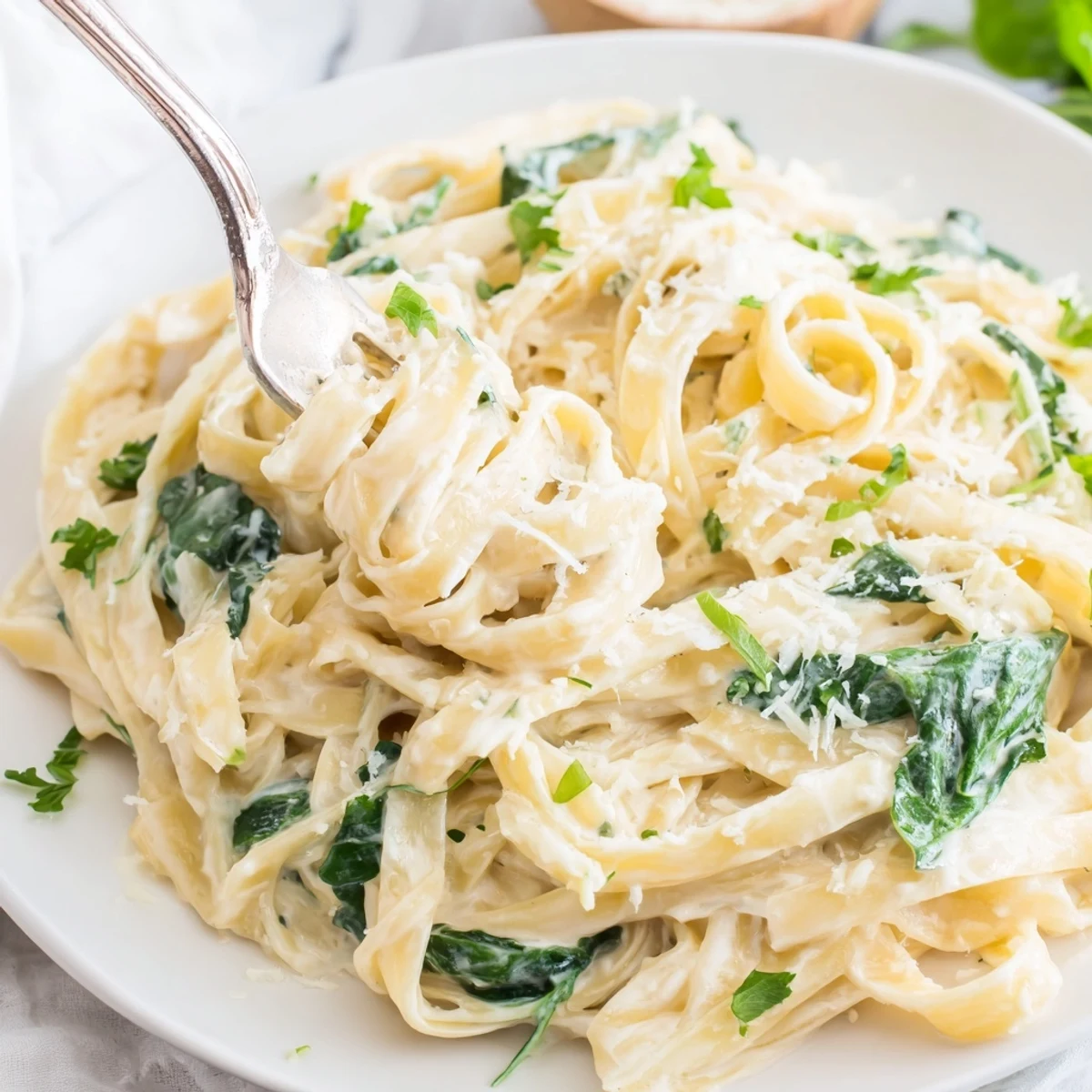 Steaming bowl of creamy spinach fettuccine Alfredo, a delicious Italian-American pasta meal.