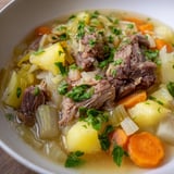A steaming bowl of Welsh Cawl showcases tender lamb and flavorful root veggies, ready to enjoy.