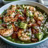 Vibrant chilli lime shrimp ceviche with fresh avocado, tomatoes, and cilantro, served chilled with lime wedges and tortilla chips.  