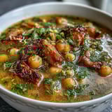 A comforting bowl of ham and chickpea soup with fresh dill, bright lemon, and tender vegetables in a savory broth.