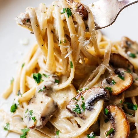 Steaming Creamy Mushroom Linguine twirls on a fork, coated in a rich, garlic-infused cream sauce with golden sautéed mushrooms.