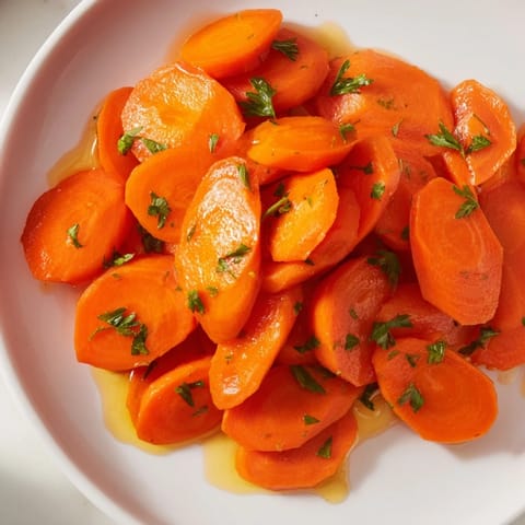 Golden honey-glazed carrots, glistening and tender, served with fresh parsley as a delicious vegetable side.