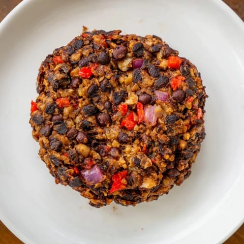 Juicy vegetarian black bean burgers sizzling in a pan, full of aromatic spices and hearty texture.