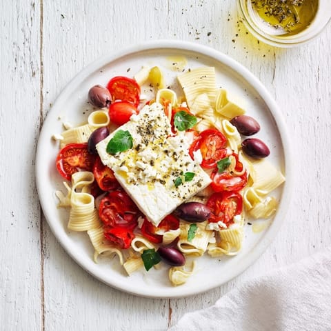 Golden baked feta pasta with vibrant tomatoes, olives, and fresh basil, ready to serve!
