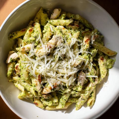 Enjoy a quick taste of the delicious 10-Minute Pesto Pasta with Chicken, garnished with fresh basil.