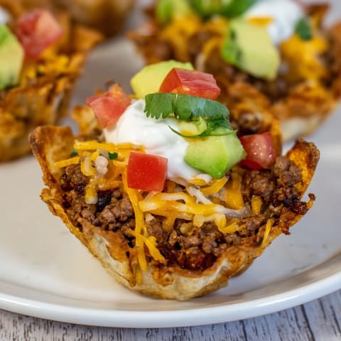 Golden-baked mini taco cups with perfectly crisp tortilla shells, brimming with savory beef and cheese.