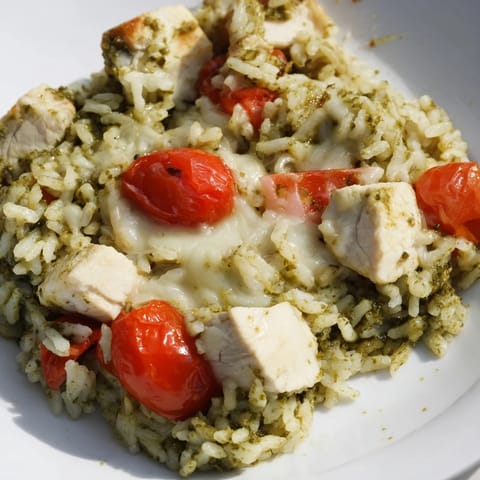 Steaming-hot, cheesy Chicken Pesto Rice Bake, ready to serve with a garnish of fresh basil.