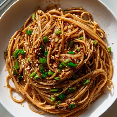 Close-up of perfectly coated Garlic Chili Oil Noodles, tossed with fresh scallions and fragrant oil.