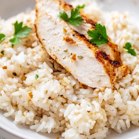 Garlic Butter Rice with Chicken presented in a white bowl, garnished with fresh parsley and bright lemon wedges for a vibrant meal.