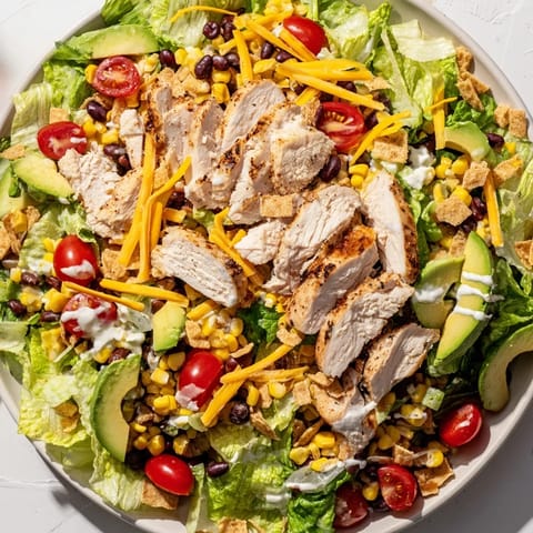 A serving bowl of Crunchy Taco Chicken Salad with seasoned chicken, fresh romaine, diced avocado, and crushed taco shells.