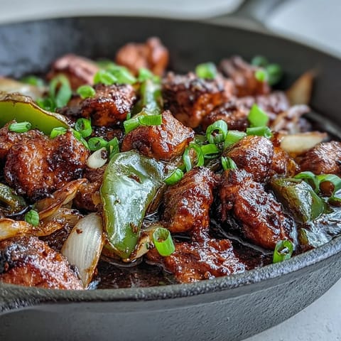 Tossing vibrant green bell pepper and onion slices with tender chicken in a savory black pepper sauce.